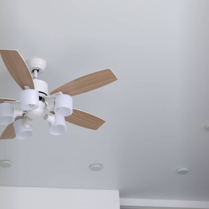A ceiling fan with wooden blades mounted on a white ceiling, viewed from below