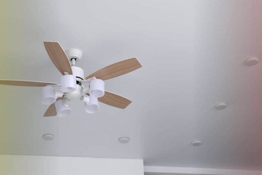 A ceiling fan with wooden blades mounted on a white ceiling, viewed from below