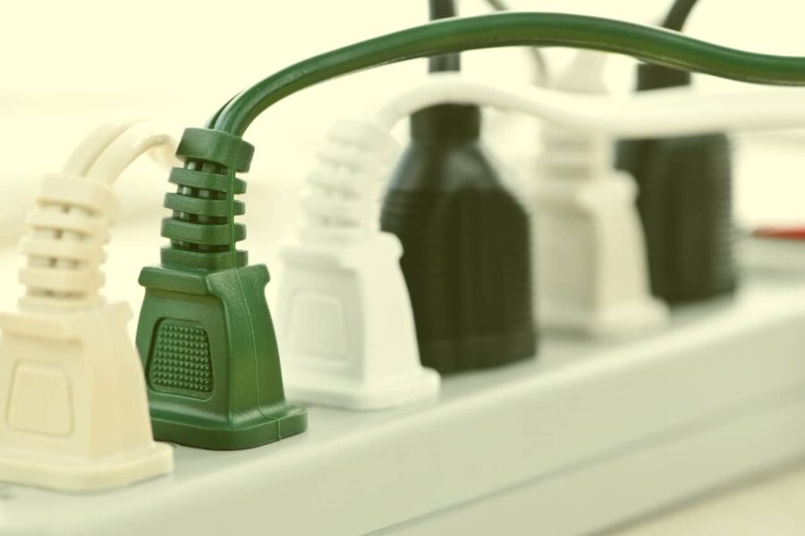A close-up view of several green, white, and black electrical cords plugged into a white power strip.
